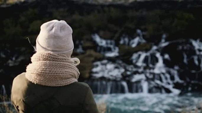 站在冰岛巴纳福斯瀑布附近欣赏风景的年轻美女的后景
