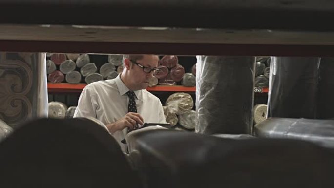 经理在仓库的数字平板电脑上书写时检查地毯
