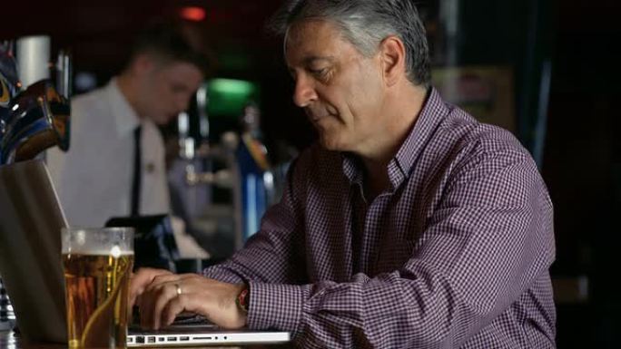 沮丧的人在酒吧用笔记本电脑喝一品脱