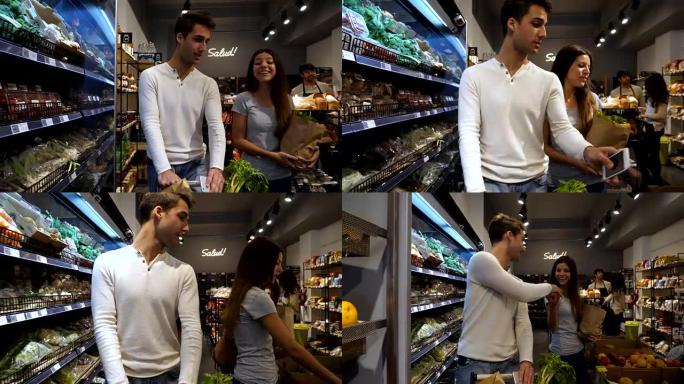 在食品市场上购买杂货的年轻幸福夫妇和伴侣将苹果传给男友，他们都微笑着