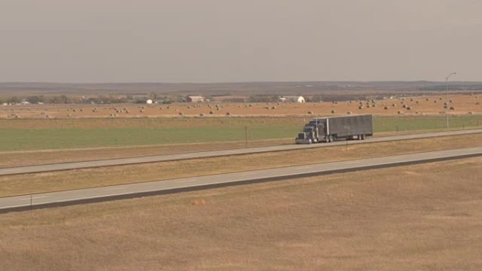 天线: 货运集装箱半卡车沿着高速公路驶过农田
