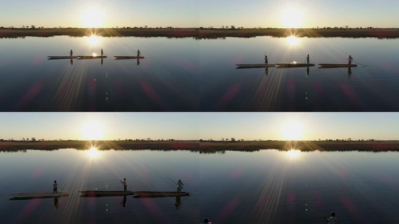 空中飞越三个划桨者的轮廓，映衬在夕阳下，划着他们的Mokoros