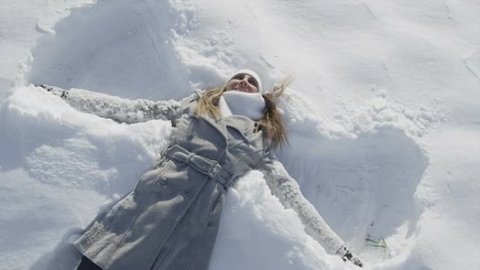 慢动作: 快乐女人在晴天做雪天使