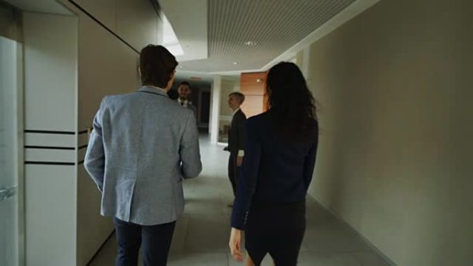 在现代商务中心，健谈的女商人和商人在大厅里散步并与同事会面并一起进入电梯的跟踪镜头