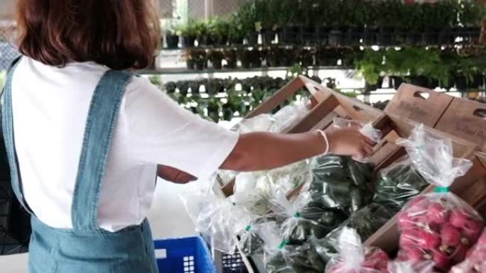 年轻女子在商店里选择蔬菜