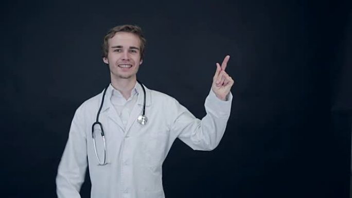 微笑的医生竖起大拇指，站在黑色背景上。包装照片