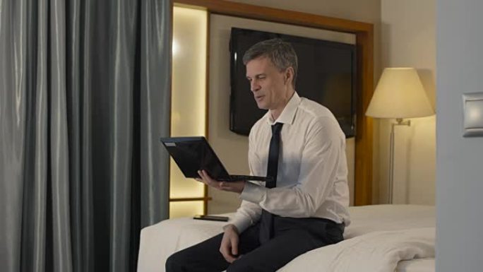 商人在酒店房间里通过笔记本电脑聊天