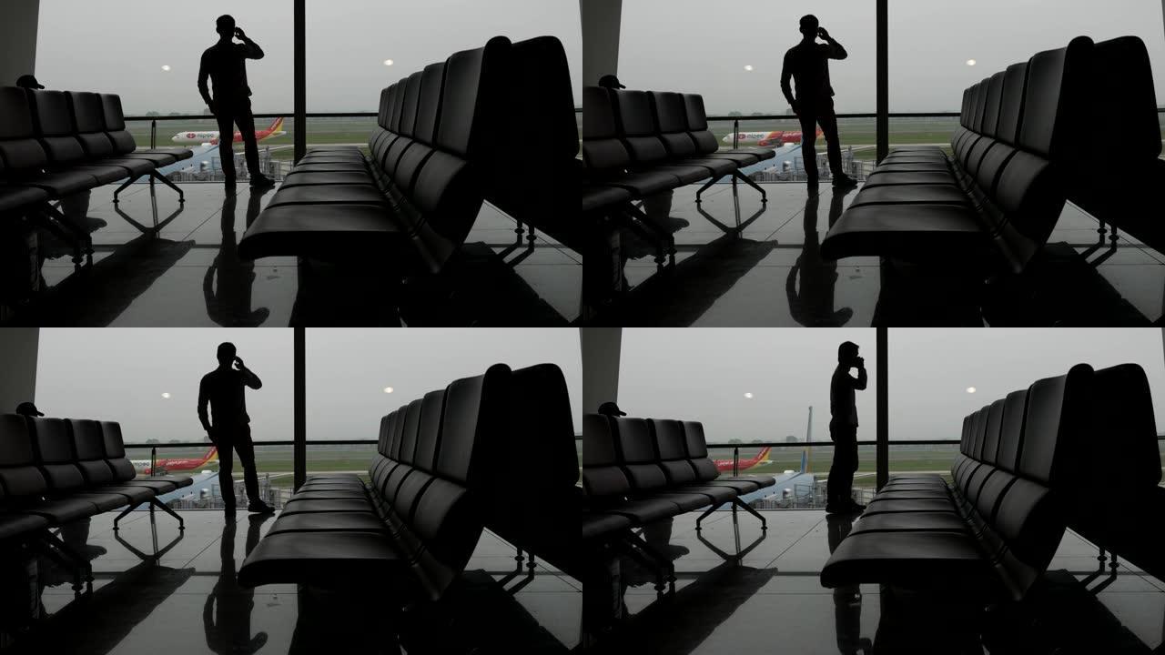 商人在机场窗口用手机聊天