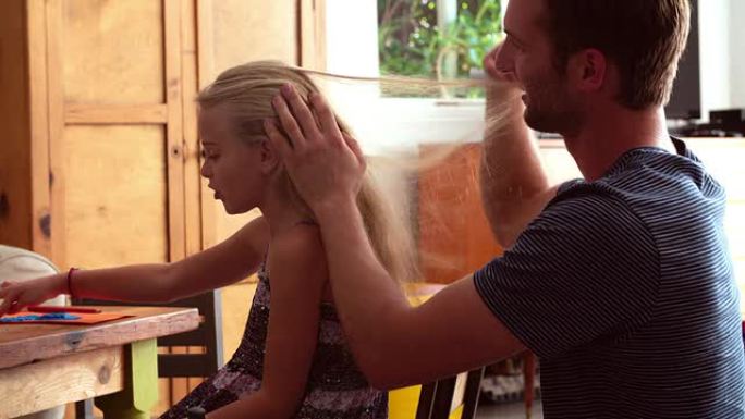 父亲坐在桌子旁刷女儿的头发