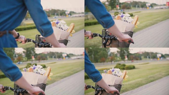 女孩手放在自行车的车把上，篮子里的鲜花和面包，在城市里骑自行车，慢动作，steadicam射击