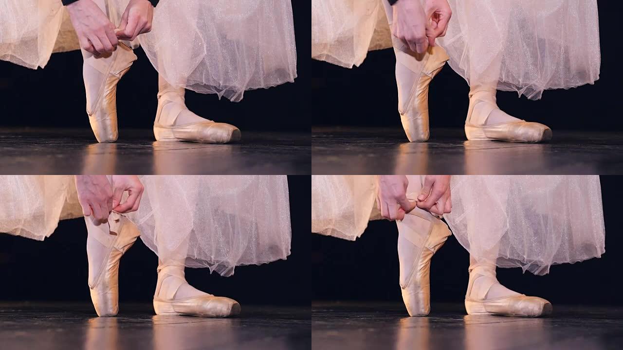 女性的手在芭蕾舞鞋上系上两条丝带。