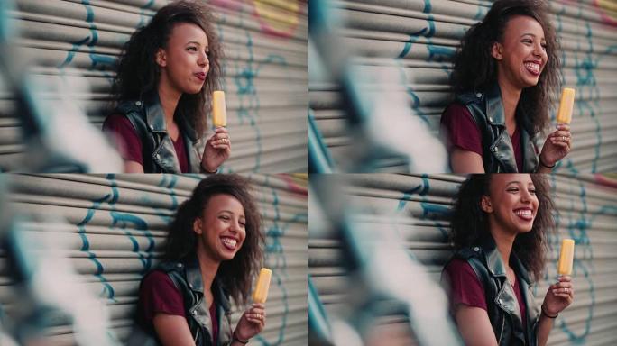 一个非洲裔美国女孩微笑着吃着一根橘子冰棍