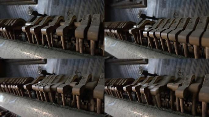 特写: 尘土飞扬的锤子在旧的破钢琴内敲击琴弦的细节