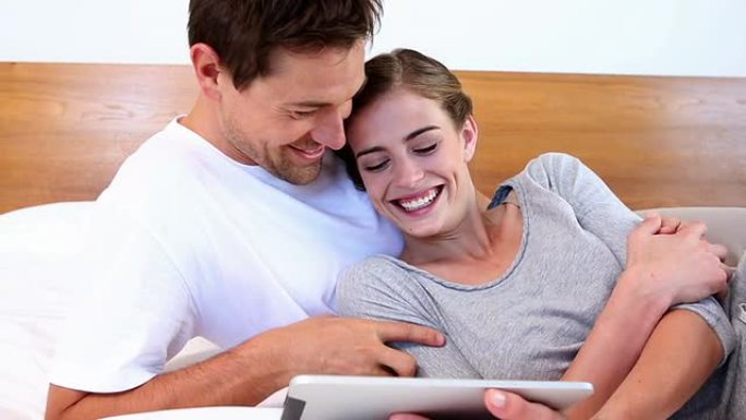 幸福的夫妻一起躺在床上使用平板电脑