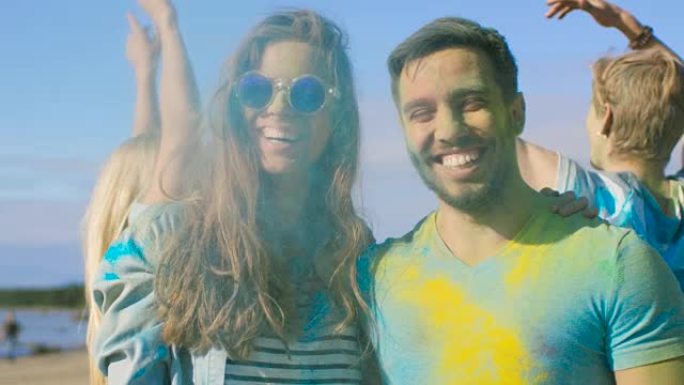在胡里节上，一对幸福的夫妇的肖像被五颜六色的粉末覆盖着。背景中的人玩得开心扔胡里粉。