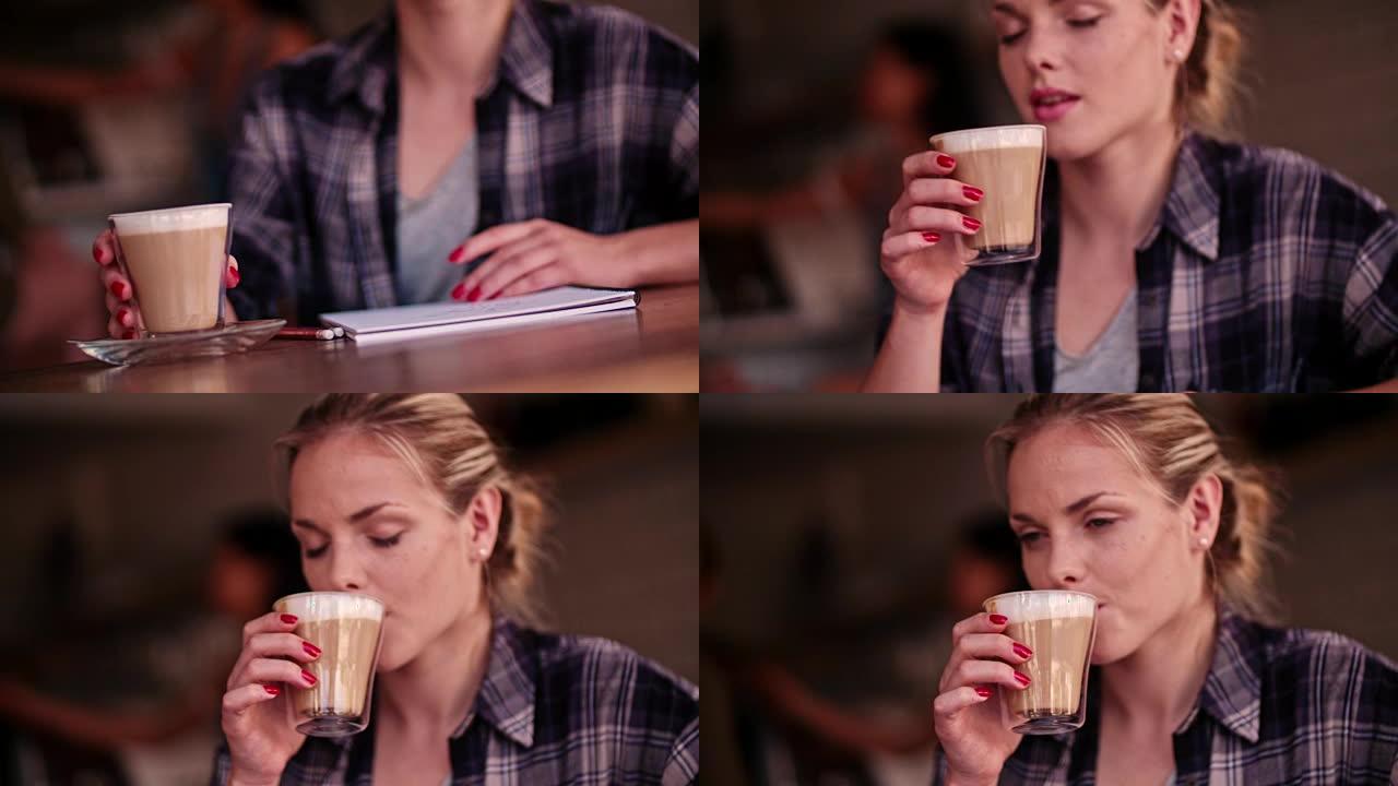 年轻的女艺术家与素描笔记本在咖啡馆喝咖啡