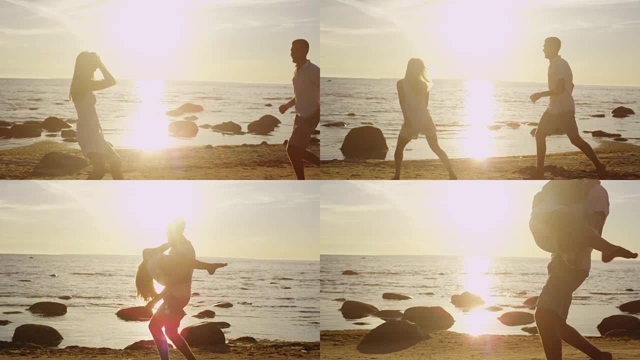 幸福的夫妇在海滩上跑步很开心。男人抱着女孩，在日落的灯光下旋转。