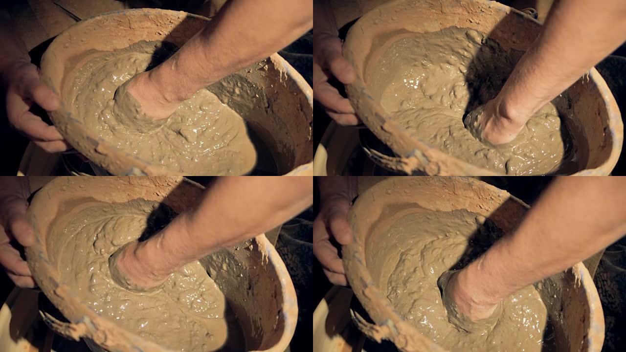 波特用手在桶里混合粘土。