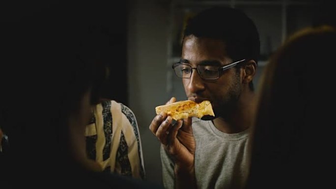 非裔美国年轻人在休闲家庭聚会上吃披萨。年轻人在家里的厨房里享受快餐