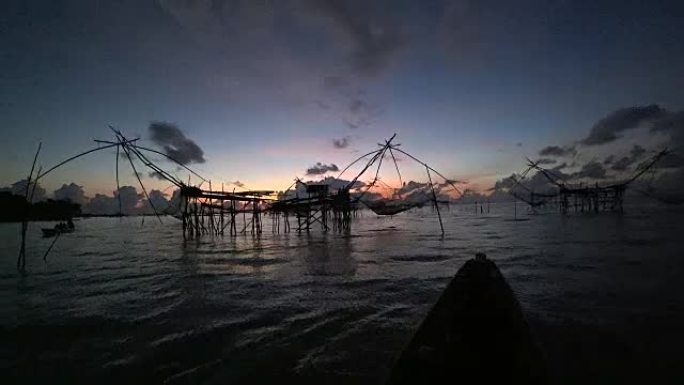 剪影亚洲渔夫在早晨日出时的工具。