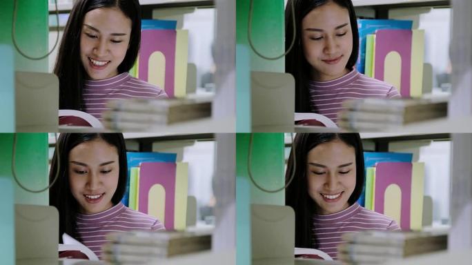 亚洲学生微笑着在图书馆看书。