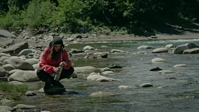 女人用溪水装满热水瓶