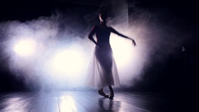 一名芭蕾舞演员在黑暗中跳跃。