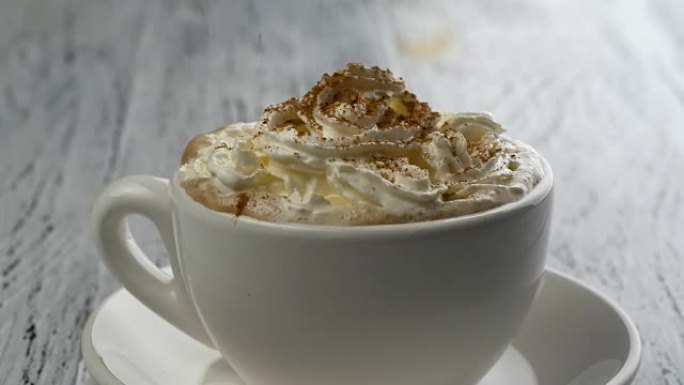 卡布奇诺咖啡杯中的肉桂粉。陈年白色木质背景