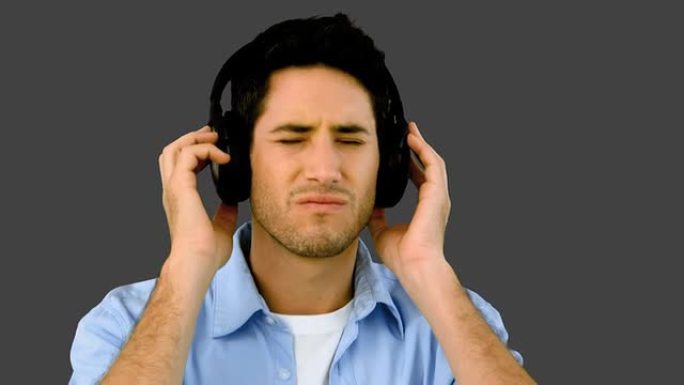 男人在灰色背景上戴着耳机听音乐