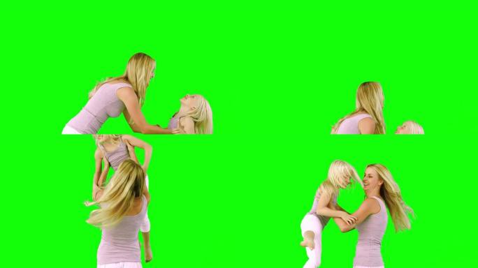 母亲在绿色屏幕上举起和旋转女儿
