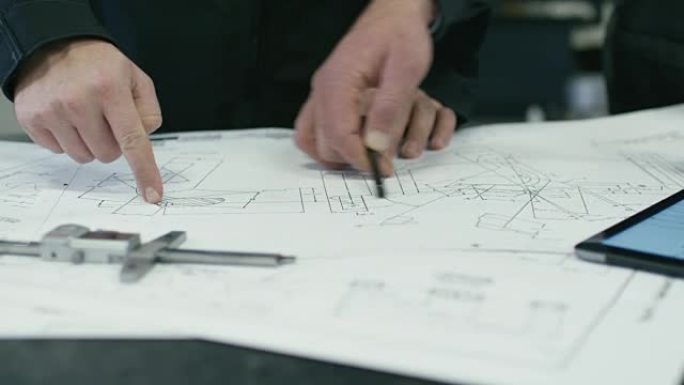 两名工程师在工厂讨论蓝图的特写镜头。