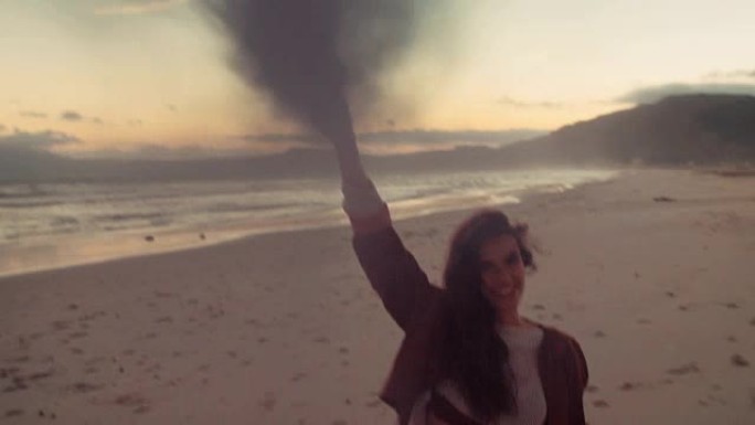 迷人的波西米亚时髦女孩带着烟雾在海滩上行走