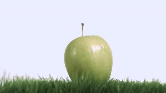 青苹果在草坪上以超慢动作落下