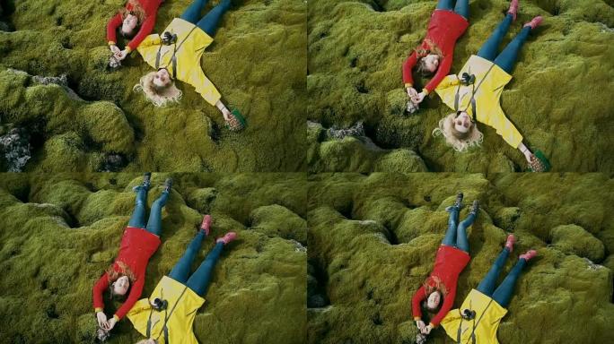 鸟瞰图，两个幸福的女人躺在柔软的苔藓在冰岛熔岩田。游客在大自然中休息