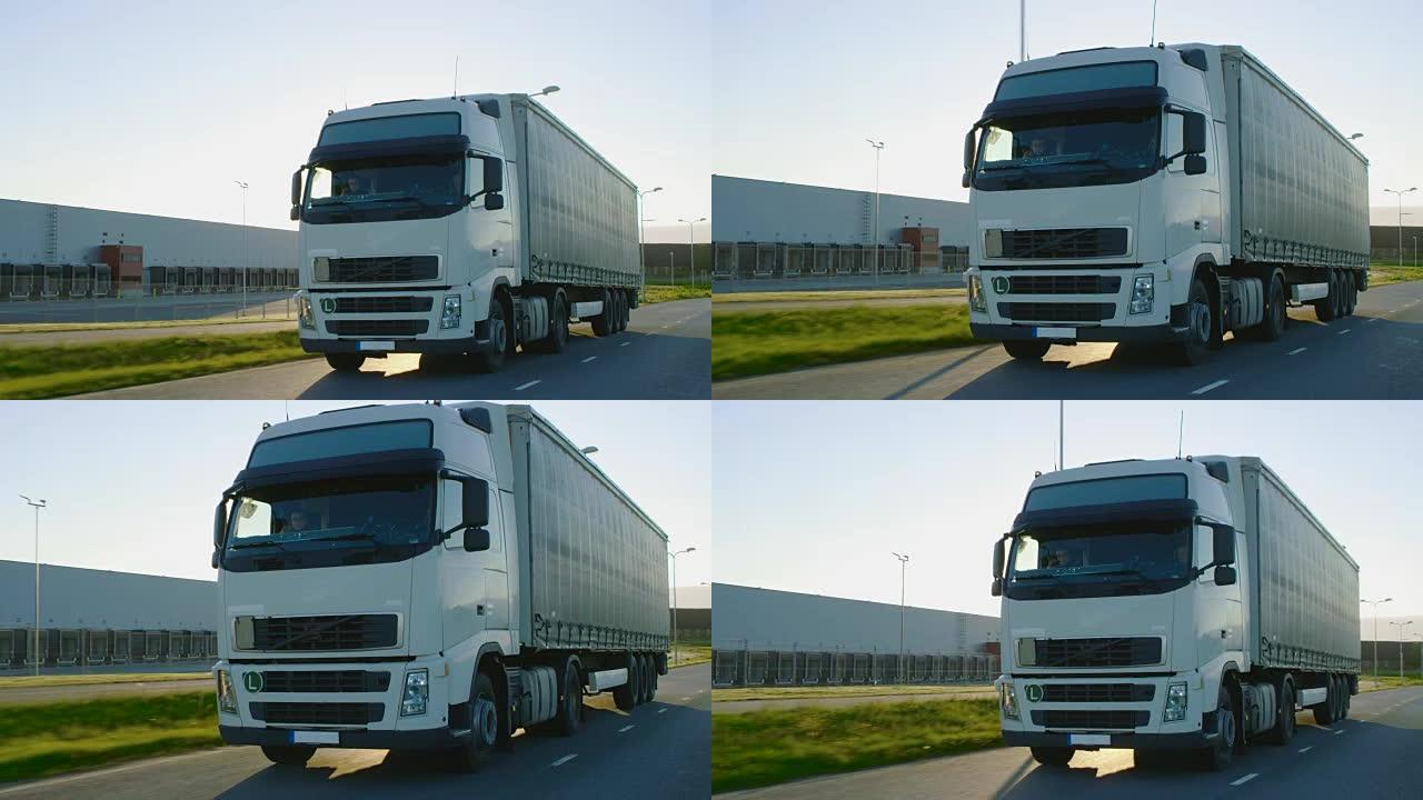 半卡车，载货拖车在高速公路上行驶。白色卡车驶过工业仓库区。
