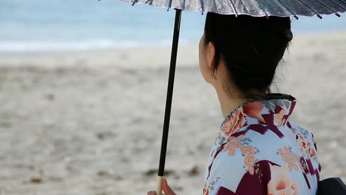 日本女人拿着遮阳伞享受大海