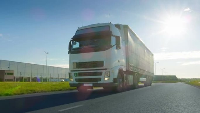 带有货运拖车的白色半卡车在工业区空旷的道路上移动，背景是阳光普照。