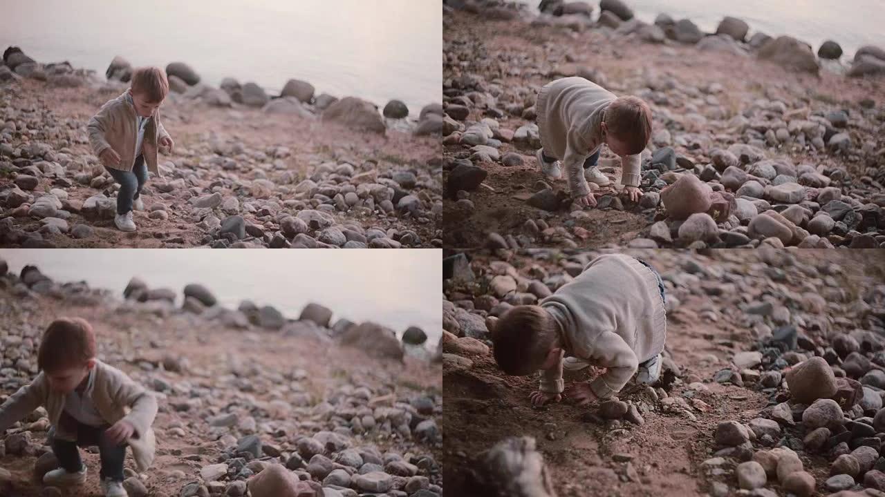 可爱的小男孩走过石头靠近水。雄性落在岩石上并上升