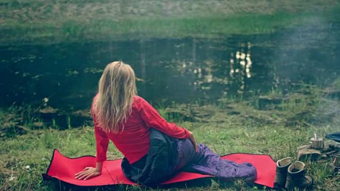 女人在湖岸放松。躺在睡袋里