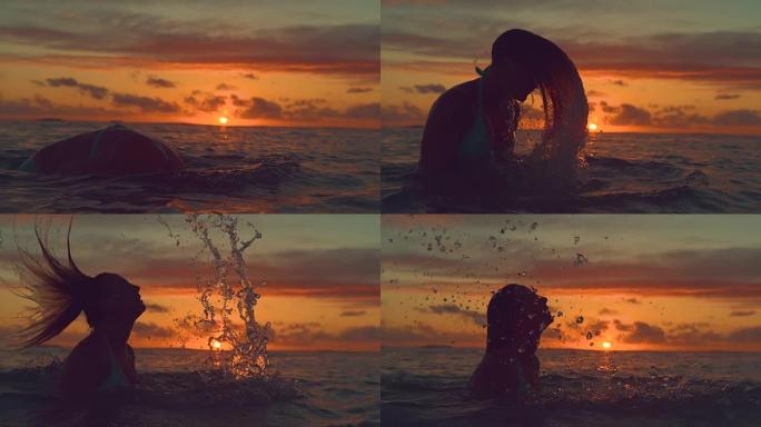 剪影: 女孩从海洋中站起来，在日出时将头向后鞭打。