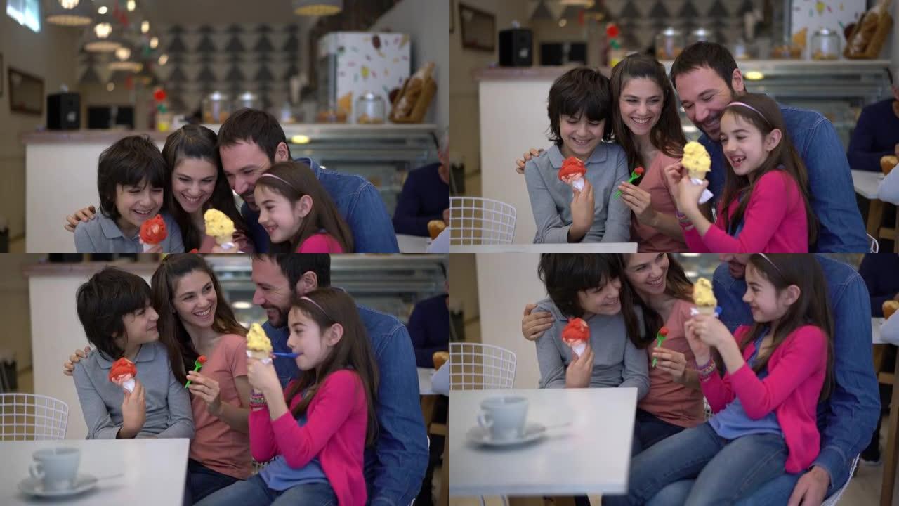 美丽的夫妇和两个孩子在冰淇淋店与他们的孩子坐在父母的每个腿上共享冰淇淋