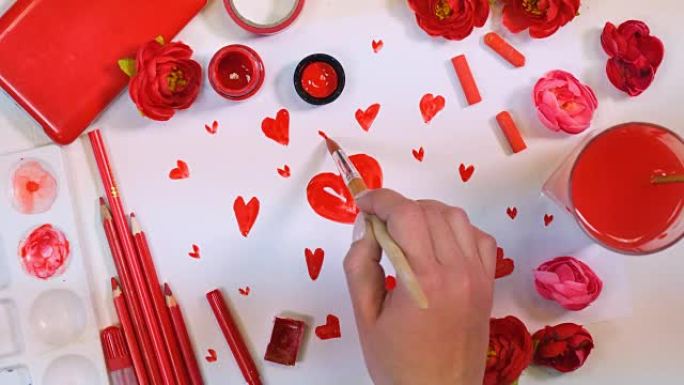 红色调色板。纸上画的许多心。艺术家办公桌从上面。情人节或母亲节概念。