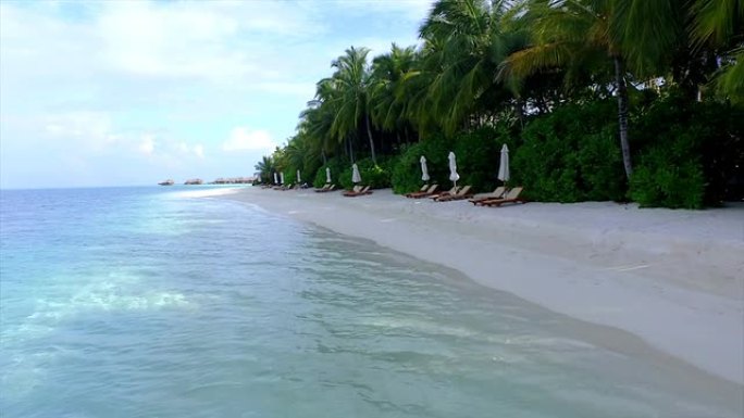 天线: 马尔代夫异国情调的白色沙滩上的空躺椅
