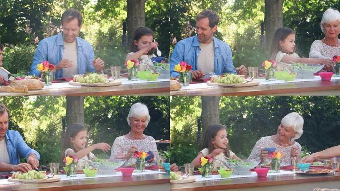 三代白人家庭在花园里吃午饭