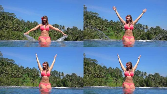 特写: 开朗的女人在巴厘岛棕榈丛林的无边泳池里泼水