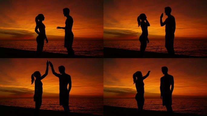 慢动作，剪影: 日落时分，年轻男女在海边击掌。