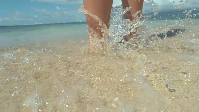特写: 无法辨认的年轻女子站在沙滩上，女人弄湿了脚