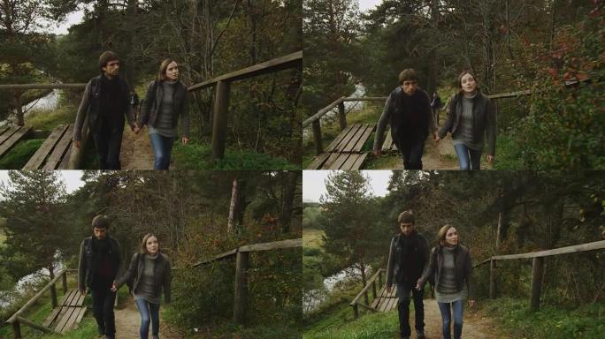 穿着秋装的夫妇正在森林小径上坡，背景是一条河。