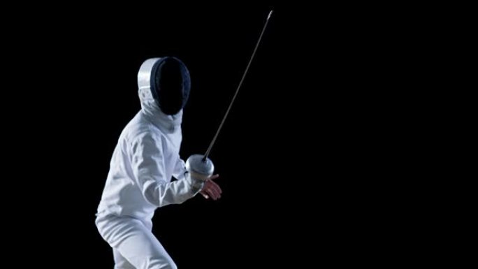 装备齐全的熟练击剑手训练用箔纸。他练习攻击，防御，跳跃，推力和弓步。拍摄孤立在黑色背景上。