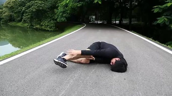亚洲跑步男子坐在马路上，抽筋的痛苦